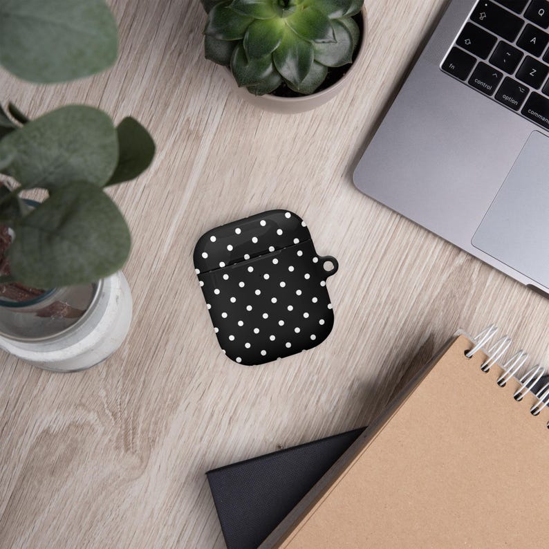 May include: A black and white polka dot Airpods case with a white strap.
