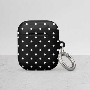 May include: Black and white polka dot silicone case for AirPods with a silver metal carabiner.