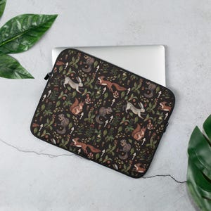 Può includere: Custodia per laptop nera con un motivo ripetitivo di scoiattoli, conigli e funghi su uno sfondo verde scuro.