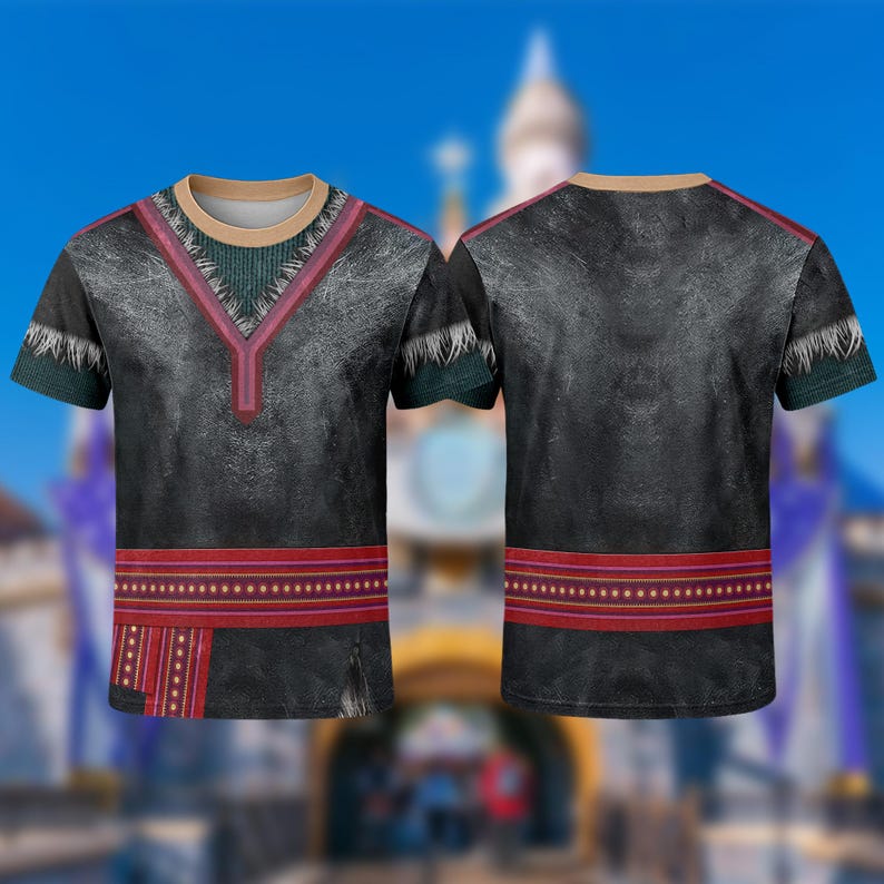 May include: A black t-shirt with a design inspired by a character from the movie Frozen. The shirt features a V-neck with red and green accents, a red band at the waist, and short sleeves. The background is blurred.