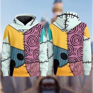 May include: A light blue hoodie with a patchwork design featuring yellow, pink, and blue panels. The design includes black stitching and spiral patterns, resembling a character from a movie. The hoodie has a white hood and cuffs.