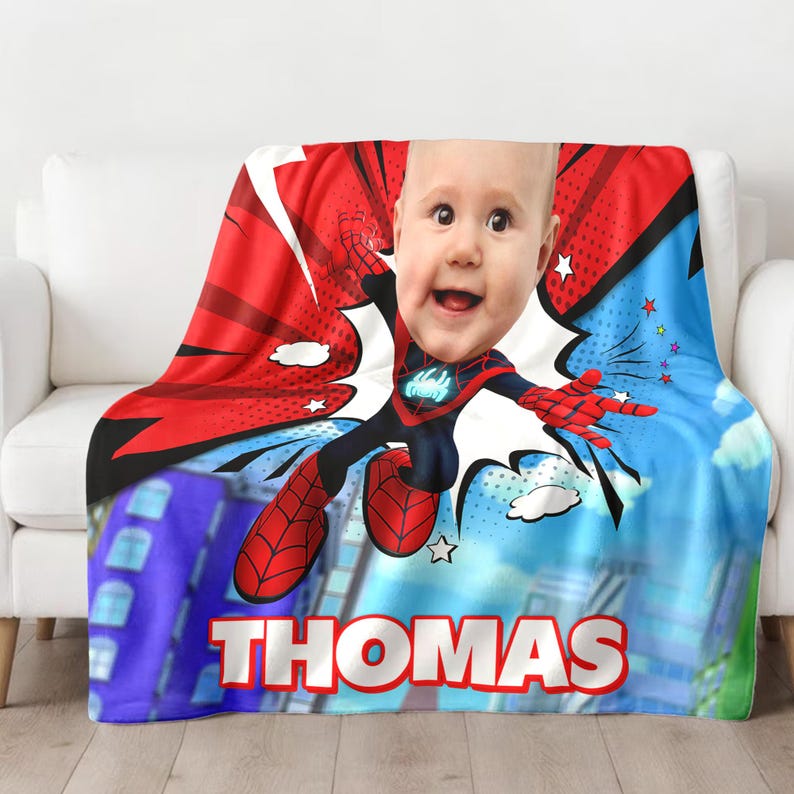 May include: A red, blue, and white fleece blanket with a cartoon superhero design. A child's face is superimposed on the superhero's head. The blanket has the name "THOMAS" printed on the bottom.