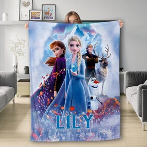 May include: A blue fleece blanket with a winter scene featuring Elsa, Anna, Olaf, and Kristoff from the movie Frozen. The blanket has the name "LILY" printed on it.