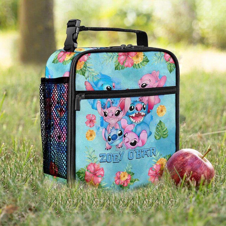 May include: A light blue lunch bag featuring cartoon characters and floral designs. The bag has a black handle, a mesh side pocket, and a zippered front pocket. The text "ZOEY O'BAR" is printed on the front.