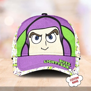 May include: Purple and green baseball cap with a cartoon image of Buzz Lightyear from Toy Story. The cap has the text "Buzz Lightyear" on the front and a space for a custom name.