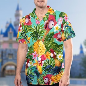 May include: A turquoise blue short-sleeved button-up shirt with a tropical print featuring cartoon roosters, pineapples, and palm leaves.