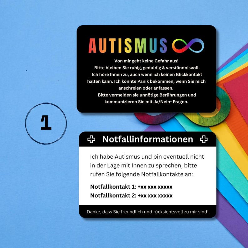 May include: A black card with the word "AUTISMUS" in rainbow colors and an infinity symbol. The card also includes text in German explaining that the person has autism and may need help communicating. The card also includes two emergency contact numbers.