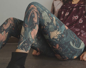 May include: A woman wearing a burgundy floral print blouse, floral leggings, and a light pink trench coat. The leggings have a dark teal background with a floral pattern in shades of peach and yellow. Black ankle boots complete the look.