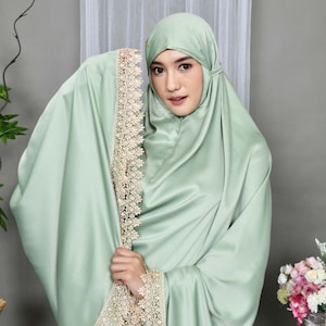 May include: A light green prayer shawl with delicate lace trim. The shawl is made of a soft, silky fabric and has a flowing drape.
