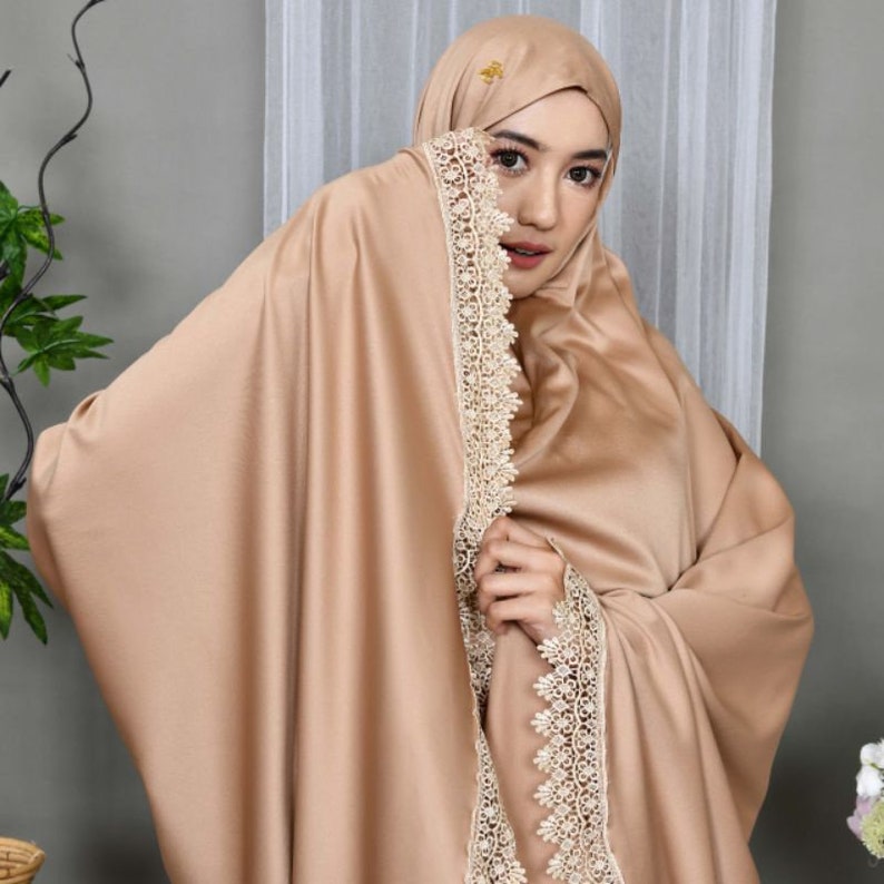 May include: A light brown prayer shawl with a delicate lace trim. The shawl is made of a soft, silky fabric and has a subtle sheen.