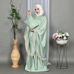 May include: A light green prayer shawl with lace trim and a matching prayer rug. The shawl has a hood and is made of a soft, silky fabric.