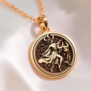 taurus woman zodiac gold pendant necklace, polished on bail and outer rim; darkened/oxidized interior field of pendant, circular pendant with concentric grooved border; central engraved scene showing standing female figure with flowing dress, flor...