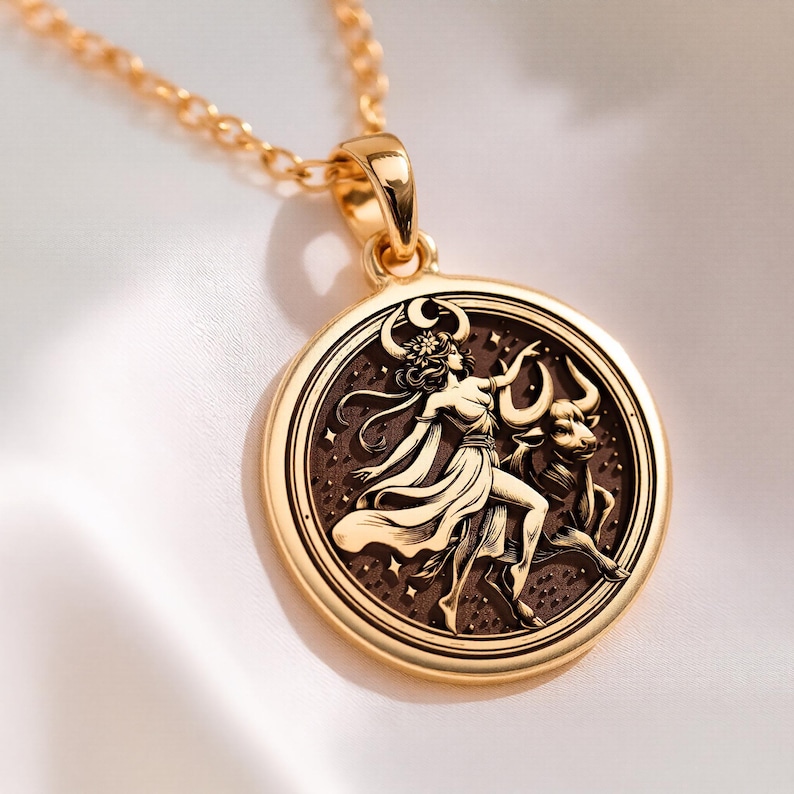 taurus woman zodiac gold pendant necklace, polished on bail and outer rim; darkened/oxidized interior field of pendant, circular pendant with concentric grooved border; central engraved scene showing standing female figure with flowing dress, flor...