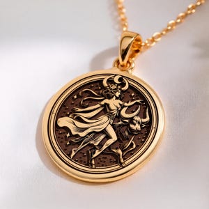 taurus woman zodiac gold pendant necklace, polished on bail and outer rim; darkened (oxidized or antiqued) background field with raised relief figures, circular medallion with concentric grooved rings around edge; central embossed scene of a stand...
