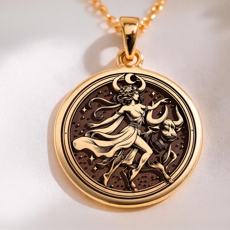 taurus woman zodiac gold pendant necklace, polished on bail and outer rim; satin/brushed on inner engraved field, circular pendant with concentric rings; central relief of a standing female figure, bull head, crescent moon above head, star motifs ...