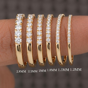 Peut inclure: Six bagues en or avec des diamants pavés disposées par largeur. Les bagues sont étiquetées 2.8MM, 2.2MM, 2MM, 1.8MM, 1.5MM et 1.2MM, montrant une progression de l'épaisseur des anneaux, chacune comportant une rangée de pierres scintillantes.