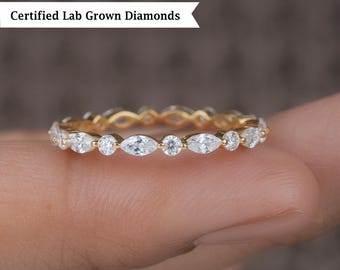 May include: A gold band with a row of marquise-shaped diamonds. The band is on a finger.