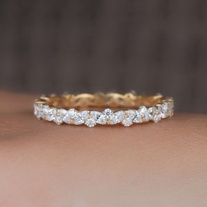 Könnte beinhalten: Ein Goldring mit einer Reihe kleiner birnenförmiger Diamanten in Pavé-Fassung.