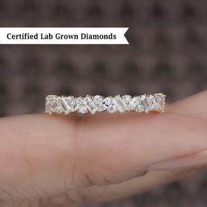 Puede incluir: Un anillo de banda de oro con una fila de pequeños diamantes transparentes, baguette y redondos.