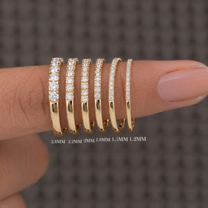 May include: Six gold rings with pavé-set diamonds arranged by width. The rings are labelled 2.8MM, 2.2MM, 2MM, 1.8MM, 1.5MM, and 1.2MM, showing a progression of band thicknesses from widest to thinnest, each featuring a row of sparkling stones.