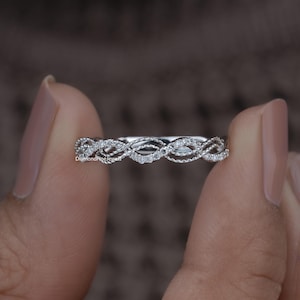 Puede incluir: Un delicado anillo de banda de plata con un diseño trenzado y pequeños diamantes brillantes.