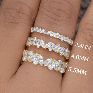 Op de afbeelding: Drie gouden ringen met heldere, marquise-geslepen edelstenen worden getoond. De ringen zijn 2,3 mm, 4,0 mm en 5,5 mm breed. De ringen zitten om een vinger. De ringen zijn waarschijnlijk voor een bruiloft of verloving.
