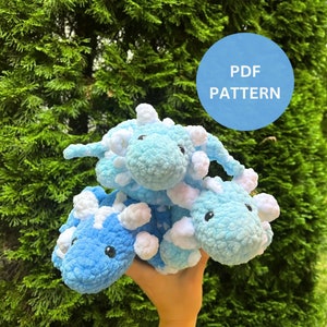 Może przedstawiać: Wzór PDF do szydełkowania pluszowego dinozaura w kolorze niebieskim i białym. Wzór jest dostępny do pobrania.