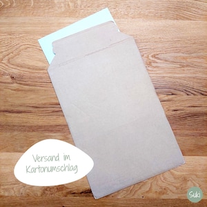 May include: A light brown cardboard envelope with a light blue card partially inserted. The envelope is open and angled, revealing the card inside. The background is a wooden surface.