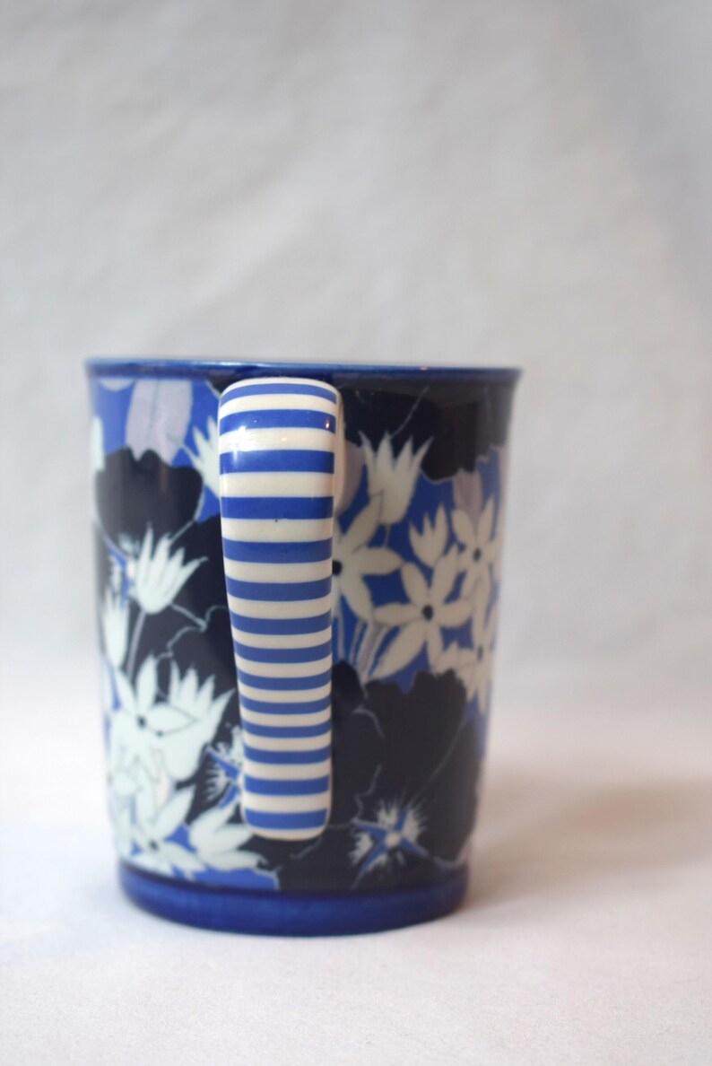 May include: A white ceramic mug with a black handle and the text "But First, Coffee" in a black, bold font. The mug is on a white surface.