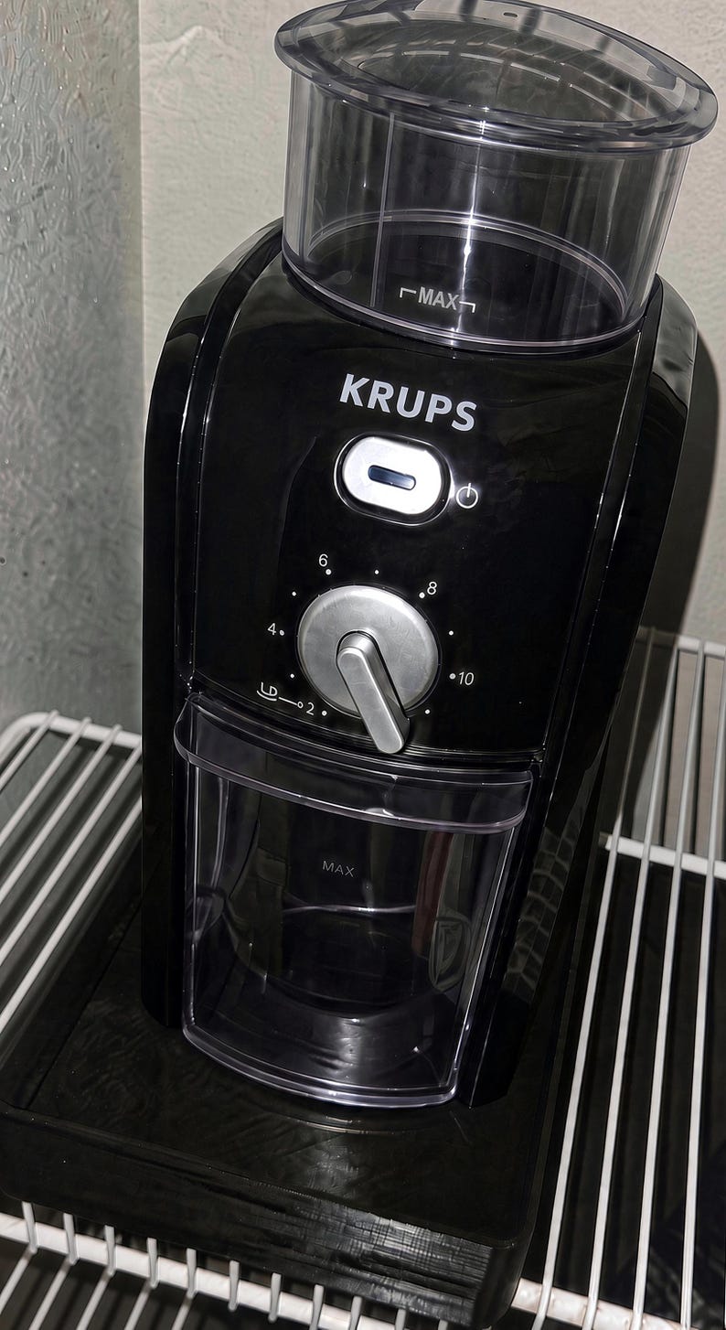 Pu&ograve; includere: Un macinacaff&egrave; nero Krups dotato di tramoggia superiore trasparente con linea di riempimento MAX, manopola centrale argentata con impostazioni da 2 a 10, pulsante di accensione e contenitore di raccolta trasparente.
