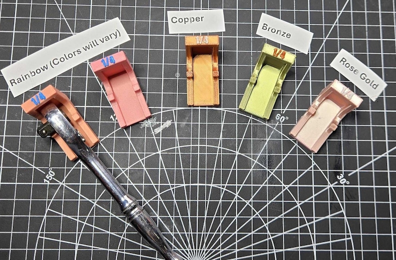 May include: Five 1/4 inch socket adapters in various colors including pink, copper, bronze, and rose gold, arranged in a fan shape. One adapter is attached to a silver metal ratchet handle. Labels identify the colors as Rainbow, Copper, Bronze, and Rose Gold.