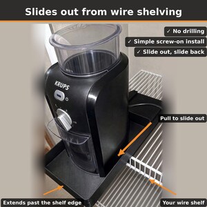 Pu&ograve; includere: Un vassoio scorrevole nero per un macinacaff&egrave; Krups su una scaffalatura in filo metallico bianco. Il testo include: Slides out from wire shelving, No drilling, Simple screw-on install, Slide out, slide back, Pull to slide out, Extends past the shelf edge, Your wire shelf.