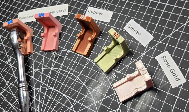 May include: Five L-shaped plastic corner brackets in various colors including pink, copper, bronze, and rose gold. Each bracket is labeled with 1/4 and is positioned next to a metal ratchet tool. Labels include Rainbow, Copper, Bronze, and Rose Gold.