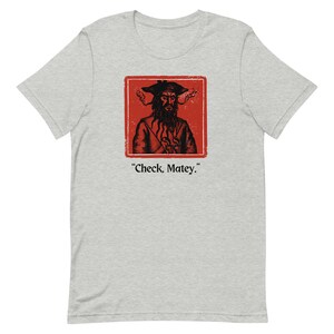 May include: A gray t-shirt with a red square featuring a black and white illustration of a pirate with a beard and a hat. The text "Check, Matey." is below the square.