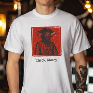 May include: White t-shirt with a red square graphic featuring a pirate with a beard and a hat. The text "Check, Matey." is printed below the graphic.