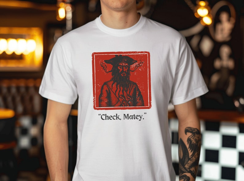 May include: White t-shirt with a red square graphic featuring a pirate with a beard and a hat. The text "Check, Matey." is printed below the graphic.