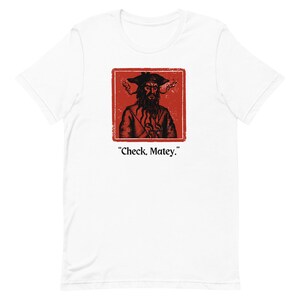 May include: White t-shirt with a red square featuring a black and white illustration of a pirate with a beard and a hat. The text "Check, Matey." is below the image.