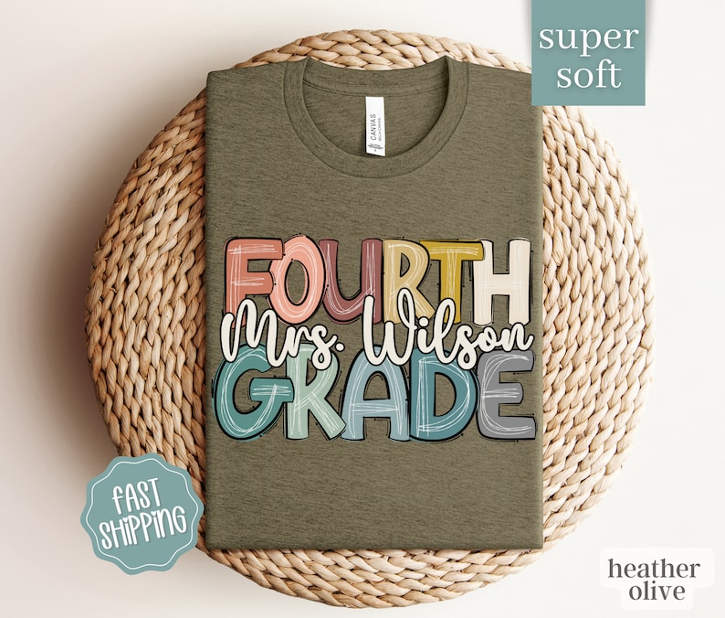 May include: A heather olive green t-shirt with the text "FOURTH Mrs. Wilson GRADE" in colorful, hand-drawn lettering.