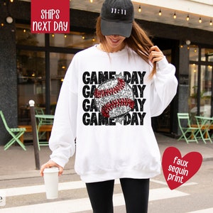 May include: White sweatshirt with a baseball graphic and the text "GAME DAY" repeated four times. The graphic is made of faux sequins.