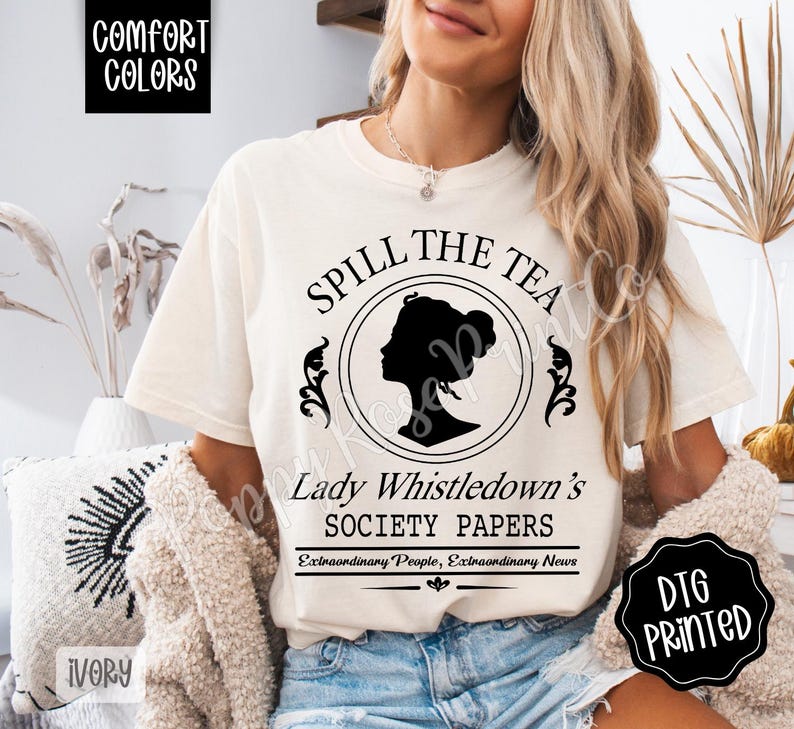 Pu&ograve; includere: T-shirt color avorio con la scritta "Spill The Tea" e "Lady Whistledown's Society Papers" in nero. Il design include una silhouette di profilo femminile all'interno di una cornice circolare. Stampa DTG.