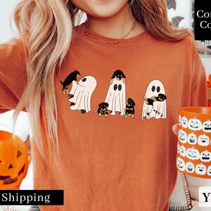 May include: Orange t-shirt with a graphic of four Rottweiler puppies dressed as ghosts. The text "Comfort Colors" is visible in the upper right corner of the image.
