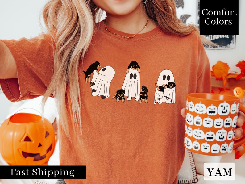 May include: Orange t-shirt with a graphic of four Rottweiler puppies dressed as ghosts. The text "Comfort Colors" is visible in the upper right corner of the image.