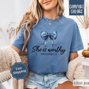 May include: A blue jean-inspired bow with a white background and the text "She is worthy Proverbs 31" on a blue t-shirt.