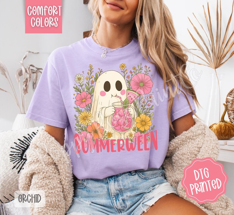 May include: A light purple t-shirt with a graphic of a ghost drinking a pink beverage with watermelon slices, surrounded by flowers. The word "SUMMERWEEN" is printed in pink. The shirt also has the words "COMFORT COLORS" and "ORCHID" printed on it.