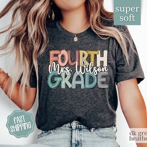 May include: Dark heather grey t-shirt with the text "FOURTH Mrs. Wilson GRADE" in colorful, outlined letters.