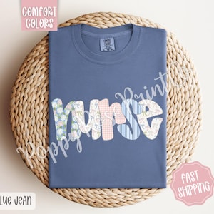 May include: A blue jean t-shirt with the word "Nurse" spelled out in colourful patchwork letters. The letters are made of different fabrics with floral and geometric patterns.