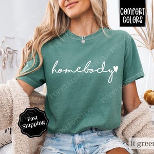 May include: A light green t-shirt with the text "homebody" in white with a small heart next to it.