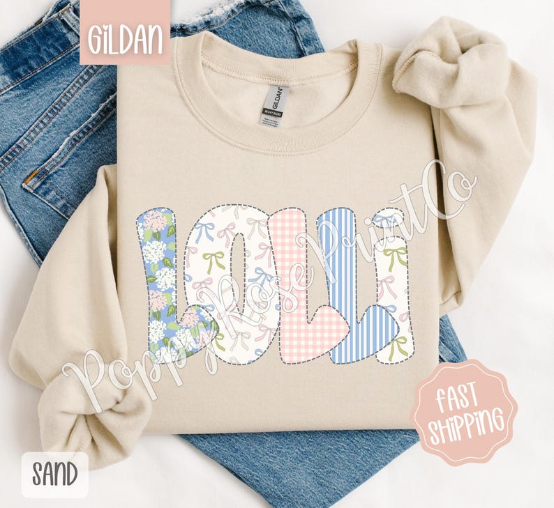May include: A beige Gildan sweatshirt with the name "Loli" spelled out in colorful patchwork letters. The letters are made of different fabrics with floral, gingham, and striped patterns.