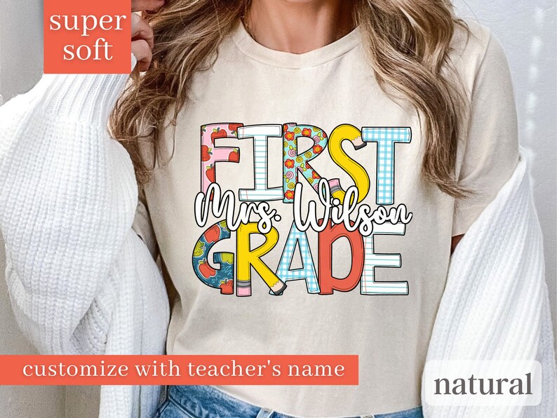 May include: A beige t-shirt with the text "FIRST Mrs. Wilson GRADE" in colourful letters with a variety of patterns. The text is customisable with a teacher's name.