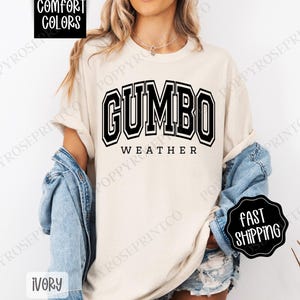 May include: A white t-shirt with black text that reads "GUMBO WEATHER" in a collegiate-style font.
